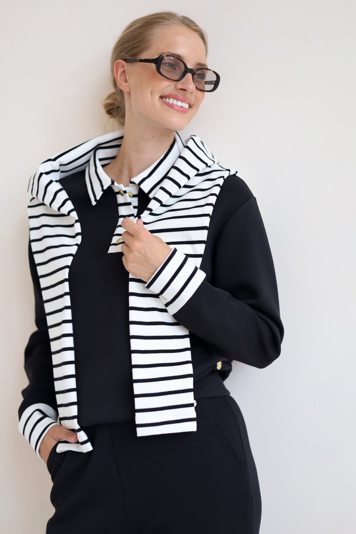 House of Gravity Button Polo Sweater in Black styled with a striped knit draped over the shoulders.