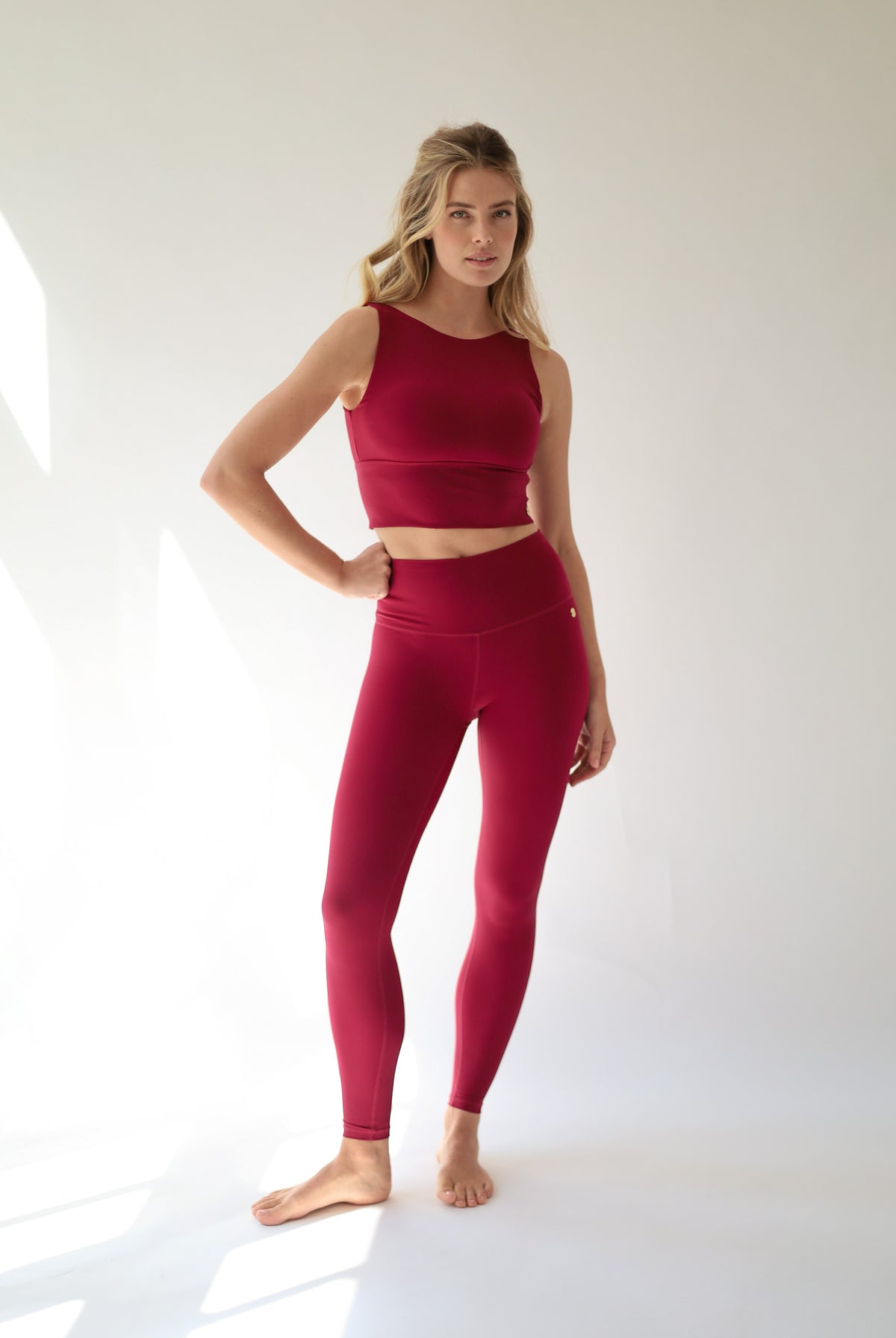 howcasing a sophisticated Deep Ruby Red activewear set, this look blends feminine strength, modern style, and performance-driven comfort against a clean white backdrop.