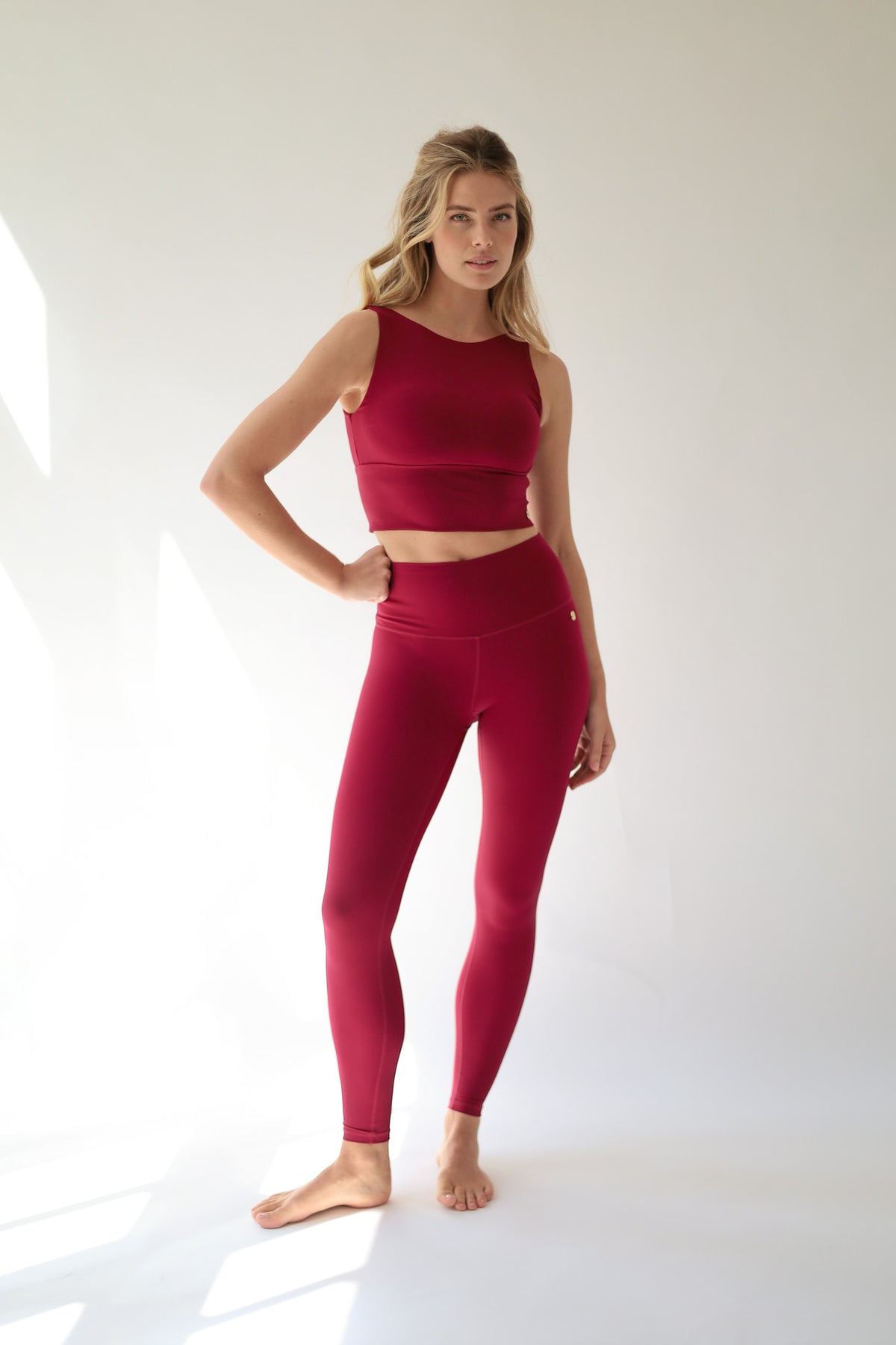 howcasing a sophisticated Deep Ruby Red activewear set, this look blends feminine strength, modern style, and performance-driven comfort against a clean white backdrop.