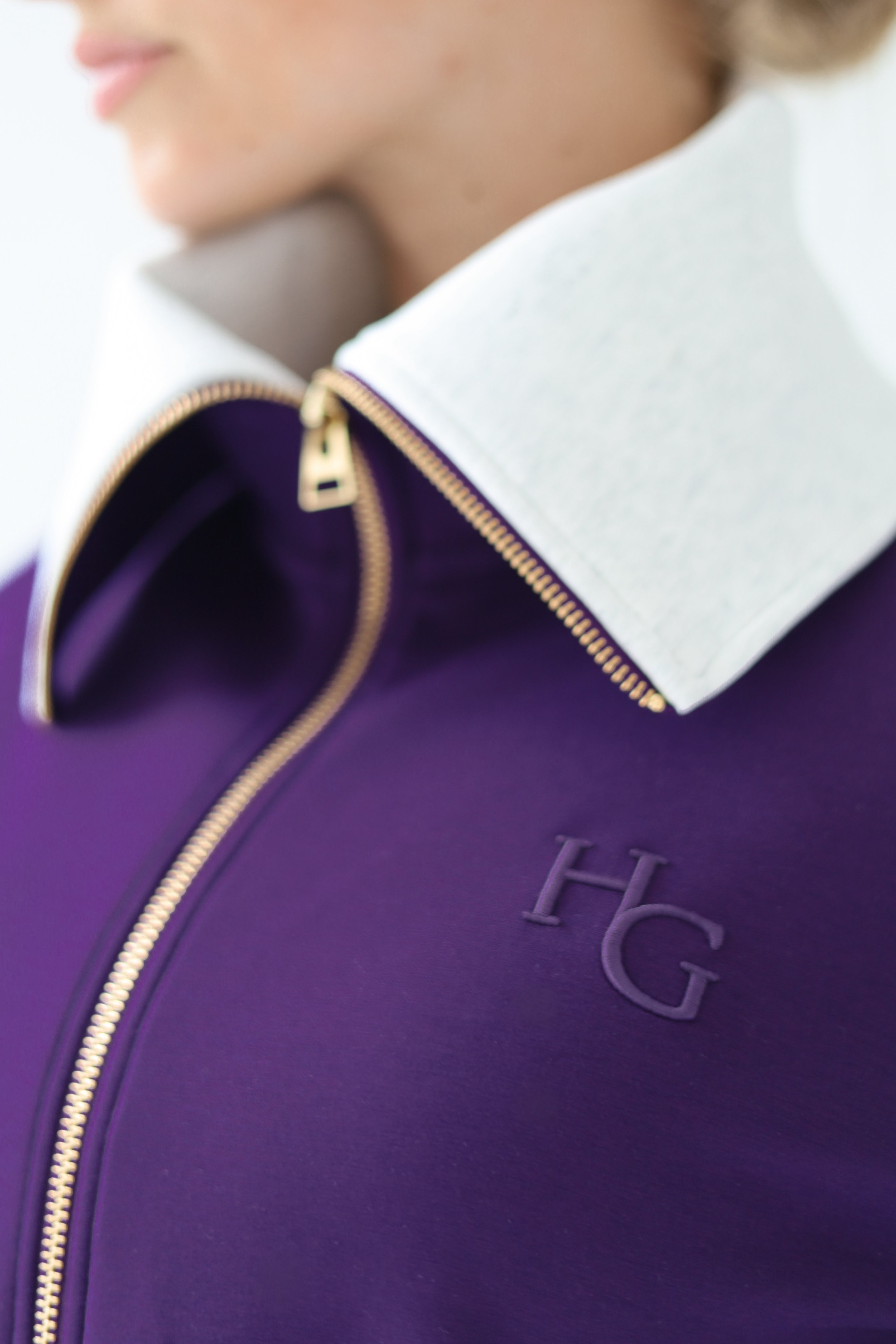 House of Gravity Turtleneck Zip Cardigan in Plum, close-up of the sculpted light grey funnel collar, gold-tone zipper, and tonal HG logo detail.