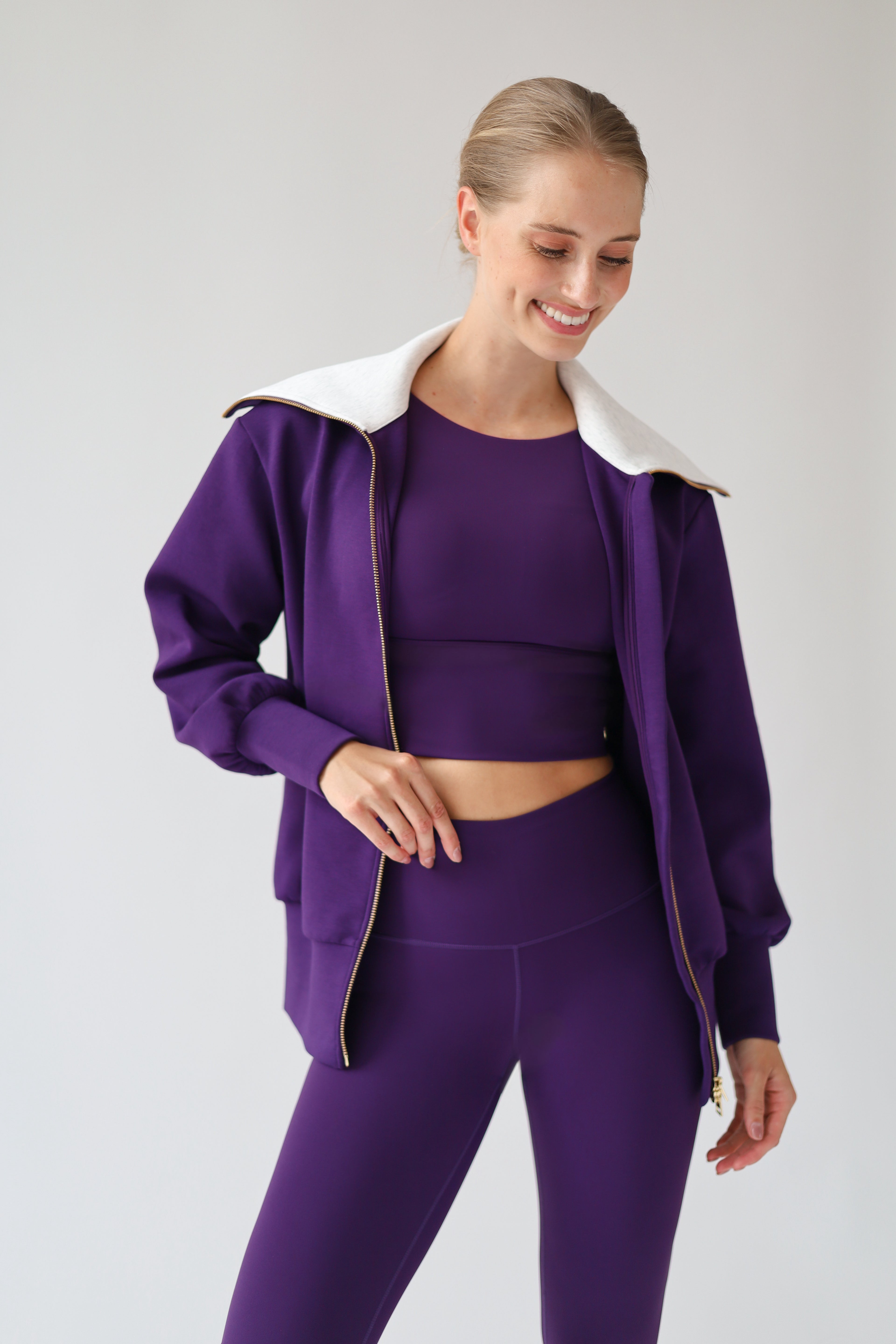 House of Gravity Turtleneck Zip Cardigan in Plum, front view close-up with the cardigan worn open, showcasing the light grey collar, gold-tone zipper, and matching activewear set.