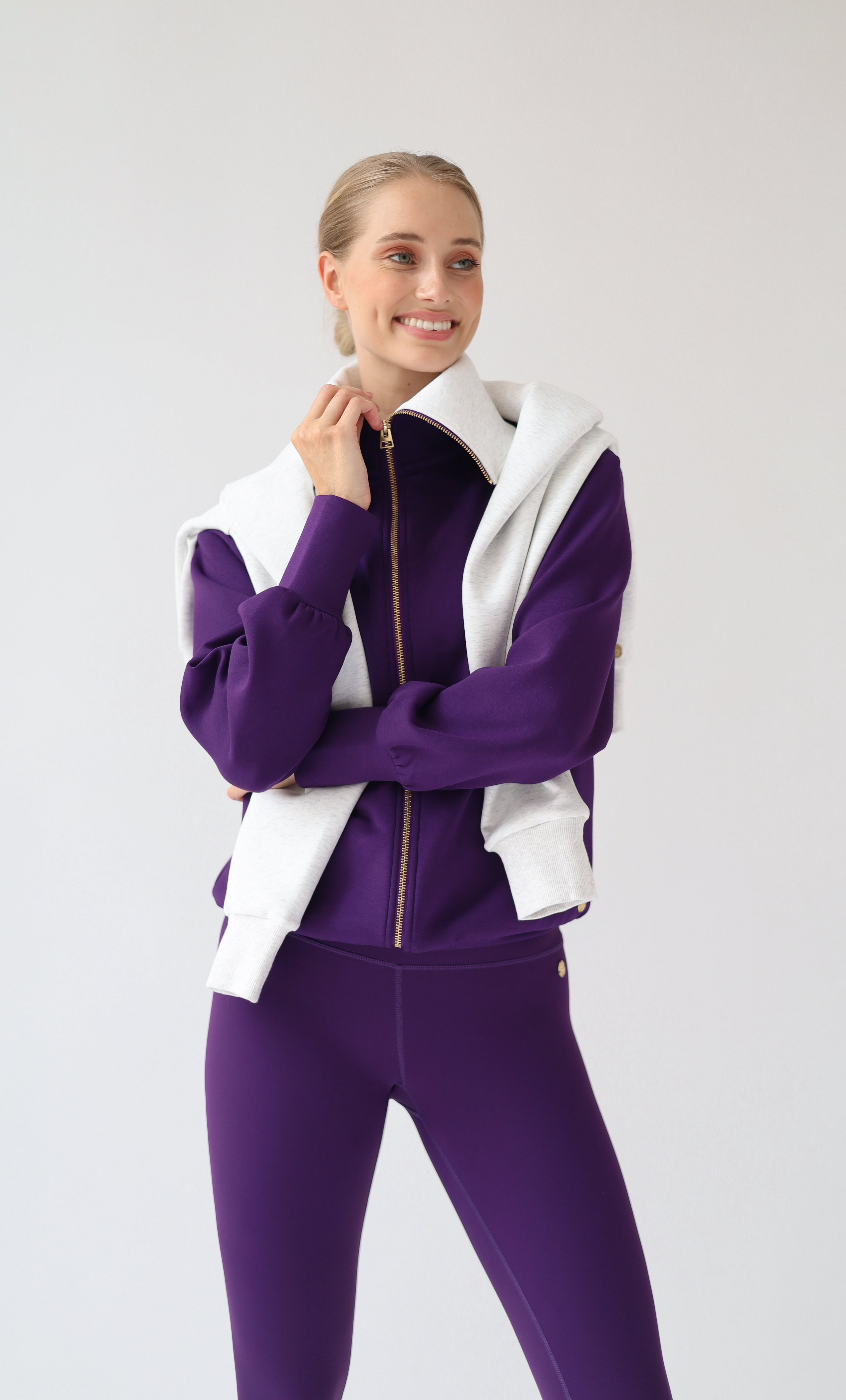House of Gravity Turtleneck Zip Cardigan in Plum, front view close-up featuring the oversized light grey collar, gold-tone zipper, matching Plum leggings, and an off-white sweater draped over the shoulders.