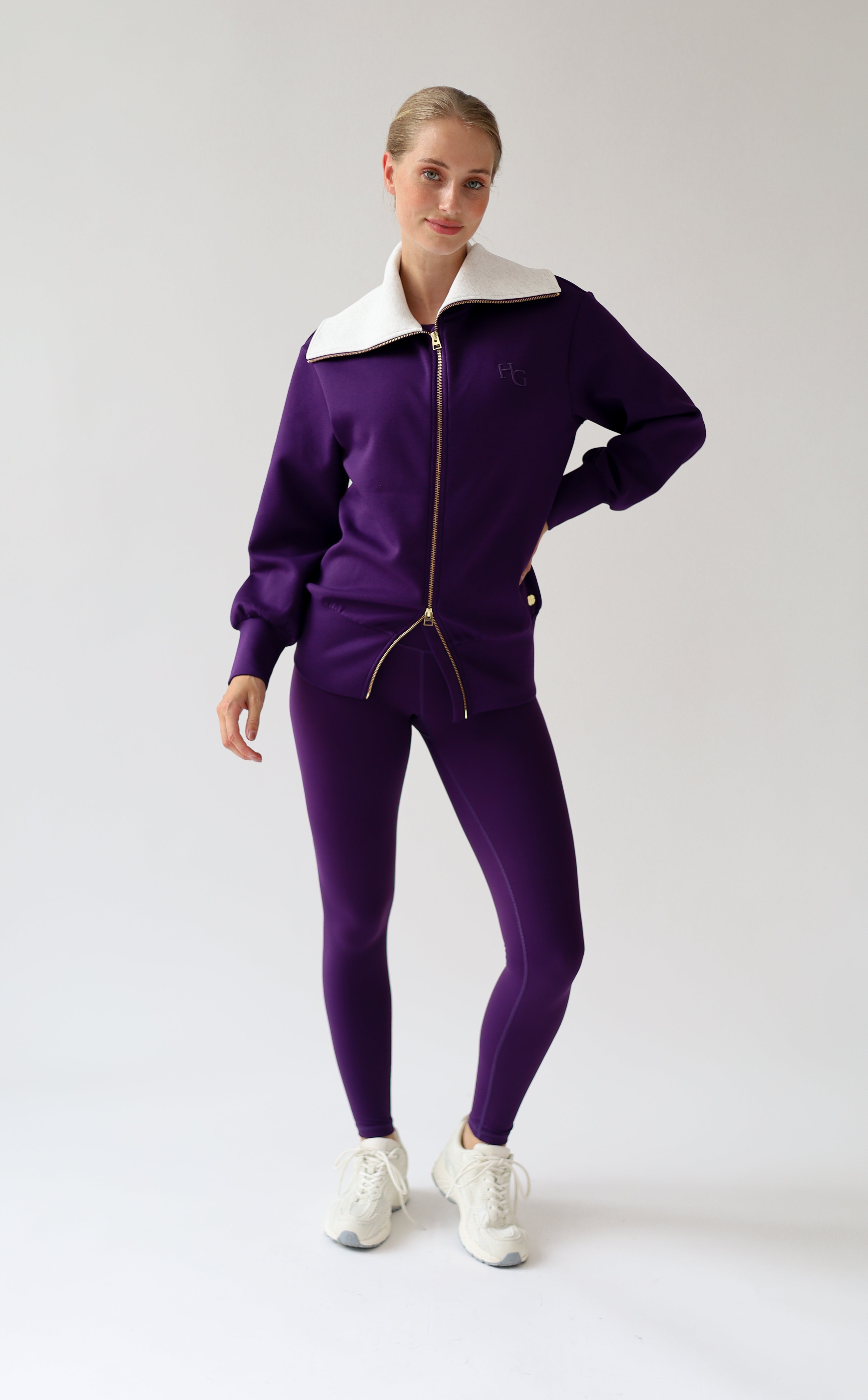 House of Gravity Turtleneck Zip Cardigan in Plum, three-quarter front view featuring the oversized light grey collar, gold-tone zipper, tonal HG logo detail, and matching Plum leggings.