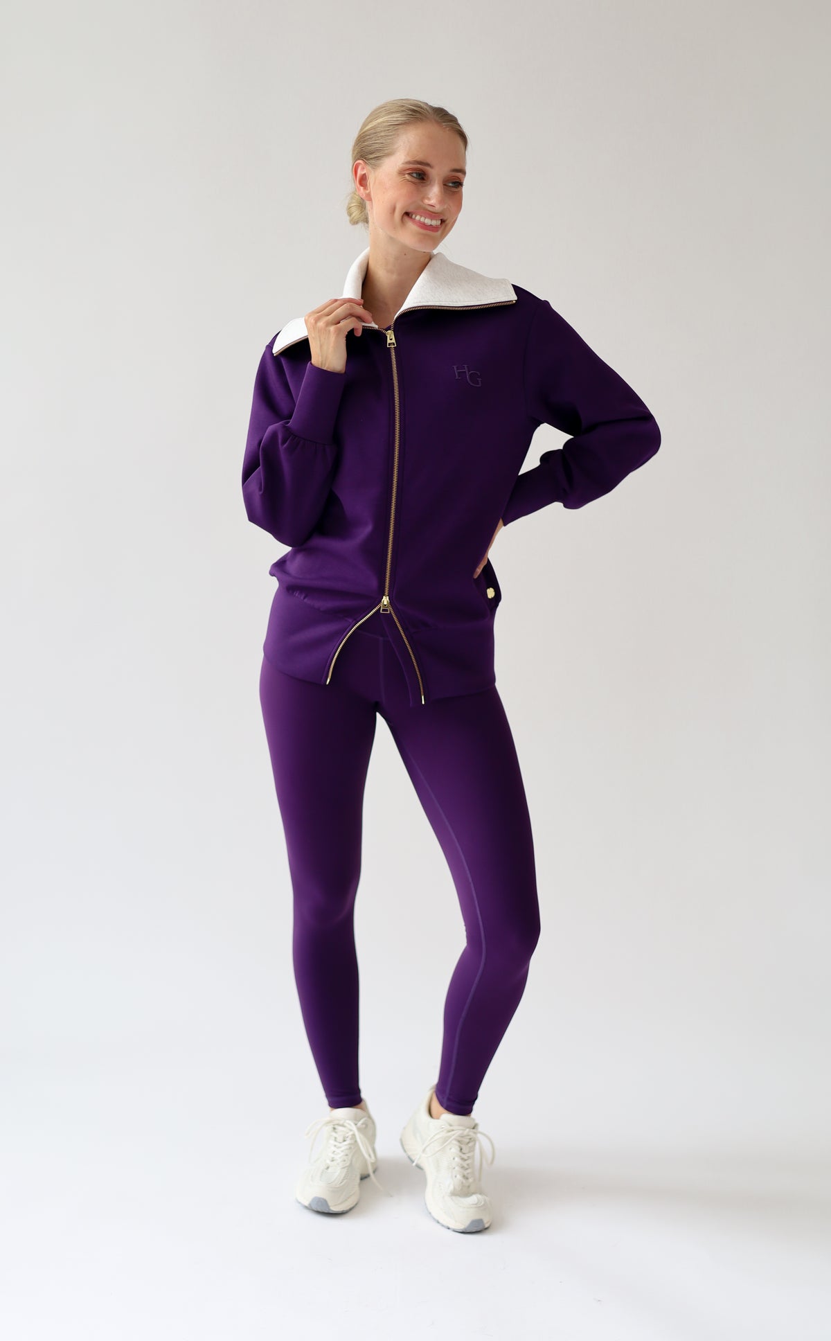 House of Gravity Turtleneck Zip Cardigan in Plum, three-quarter front view featuring the oversized light grey collar, gold-tone zipper, tonal HG logo detail, and matching Plum leggings.