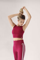 Woman wearing a red athletic outfit with white stripes on a light background
