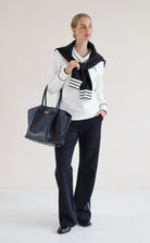 House of Gravity V-Neck Sweater in Off-White Marble and Black paired with the Wide Leg Trouser in Black, styled with a knit sweater and tote bag.